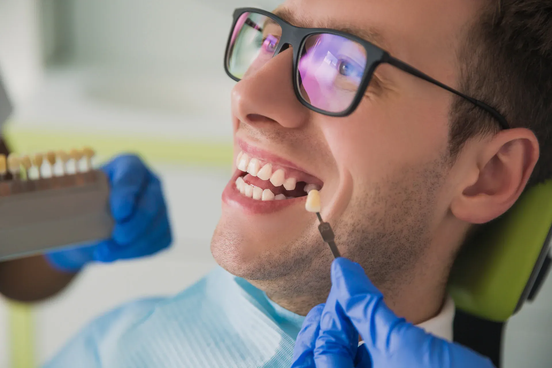 Dentist matching tooth shade guide to patient smile