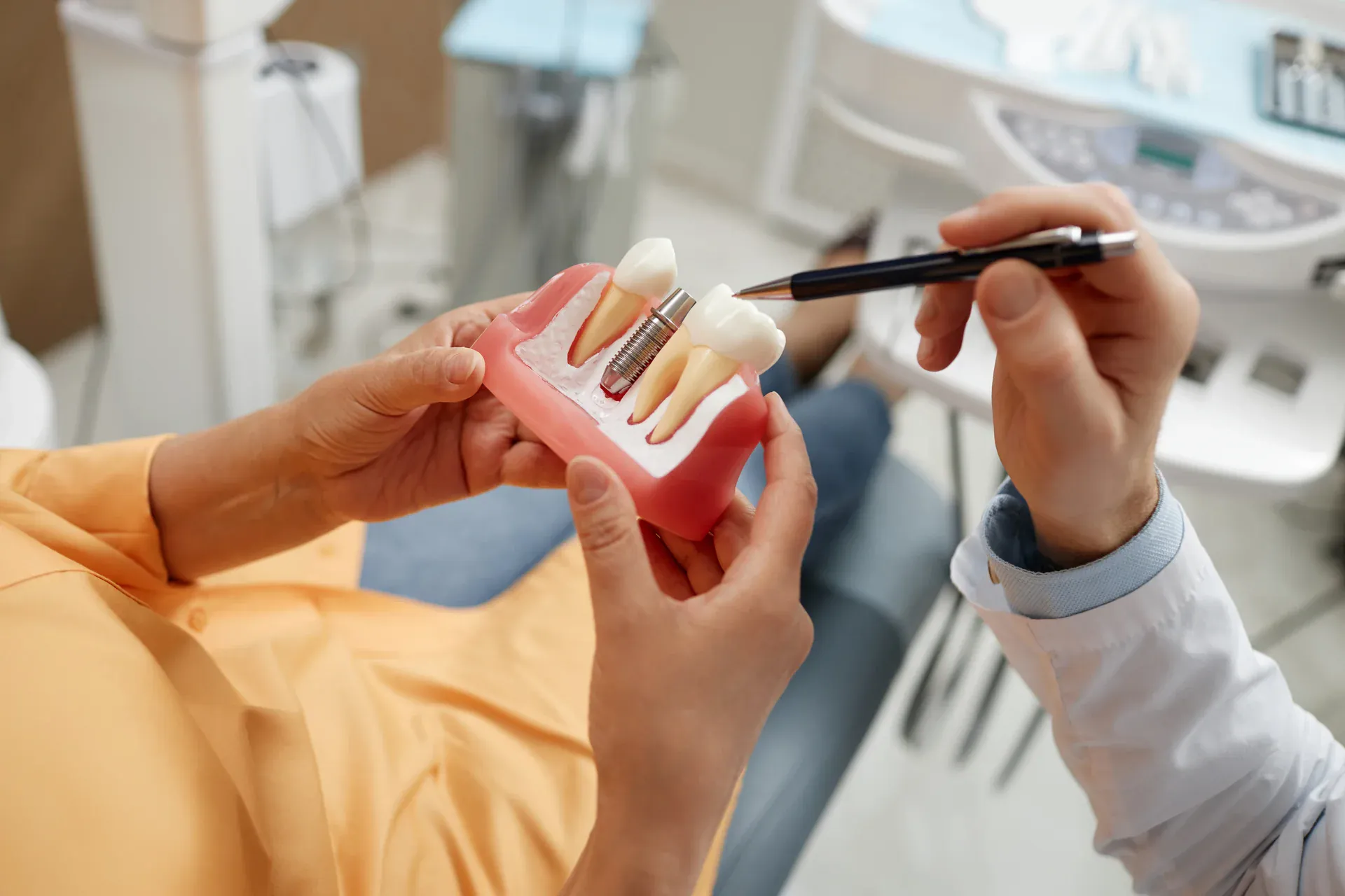 Dentist explaining dental implant model to patient in operatory