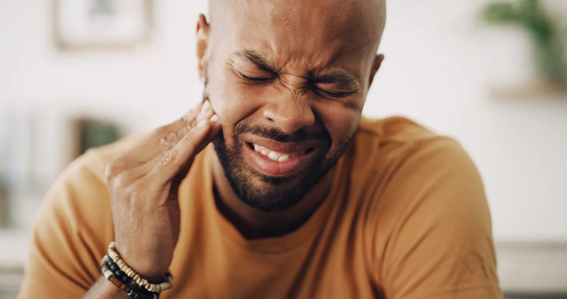 Man at home holding his cheek with severe toothache
