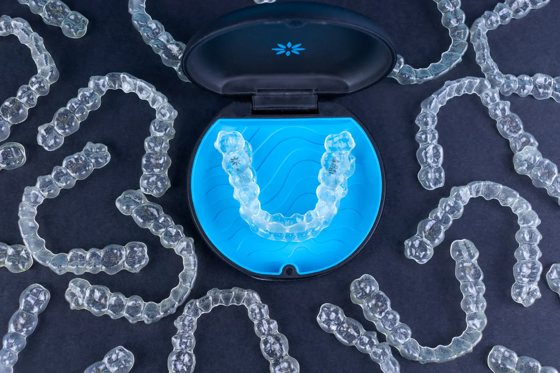 Invisalign clear aligners arranged around a blue storage case