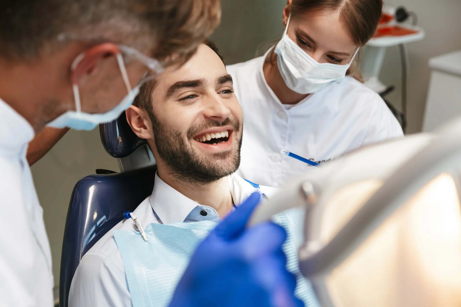 Smiling patient in dental chair with Mantena Dental team