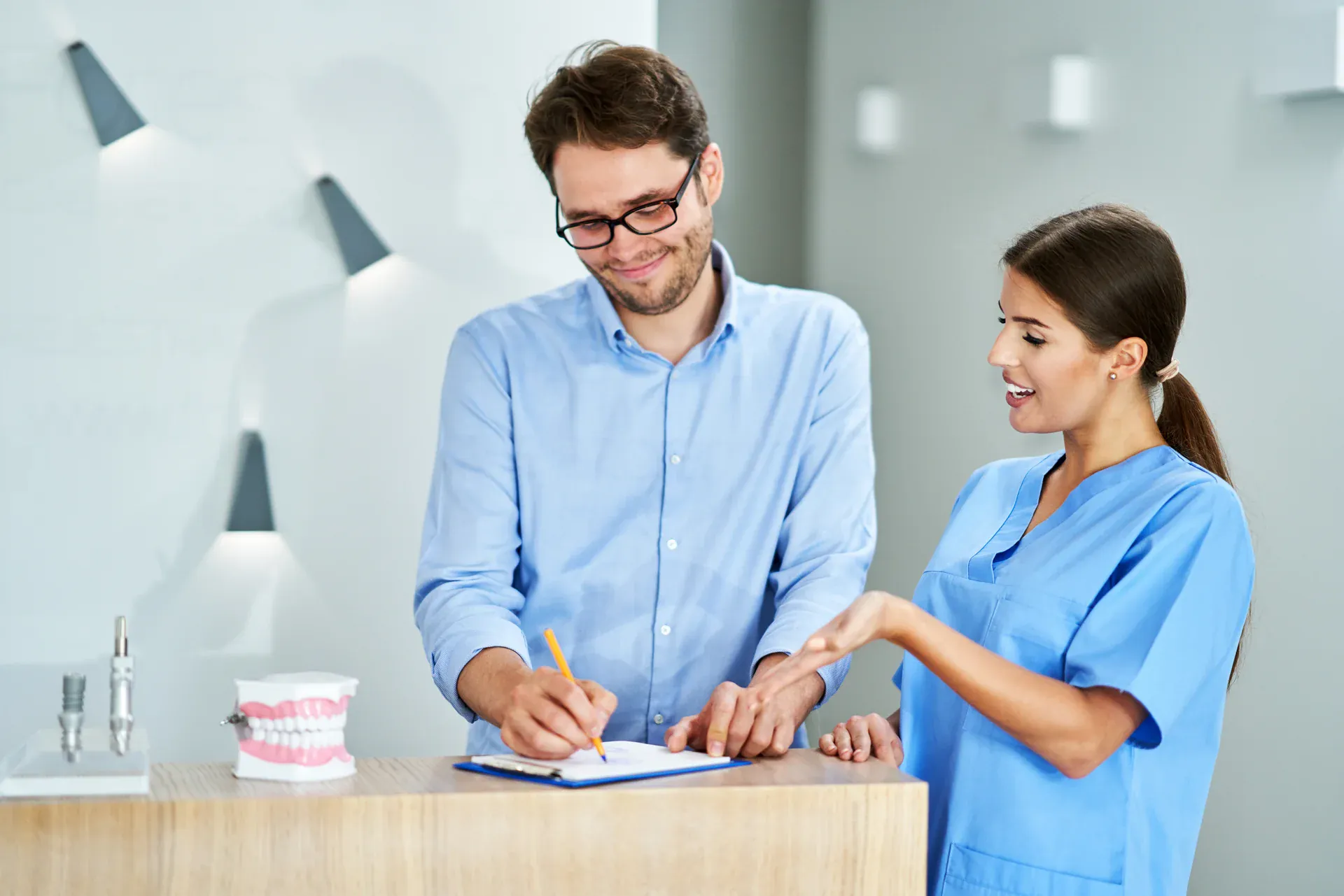 Patient completing insurance paperwork at front desk with Mantena Dental team member